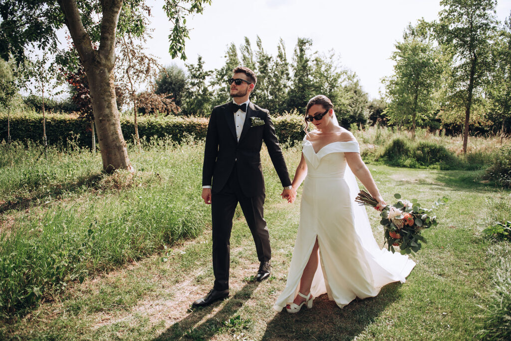 A couple swinging hands wearing sunglasses at their luxury wedding venue, behind the scenes of Editorial Wedding Photography: A Luxury Couple's Shoot