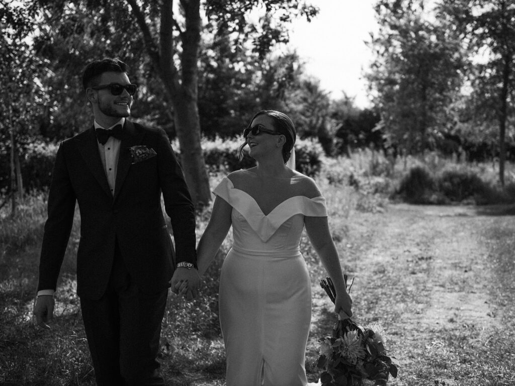 A couple walking hand in hand wearing sunglasses at their luxury wedding venue, behind the scenes of Editorial Wedding Photography: A Luxury Couple's Shoot