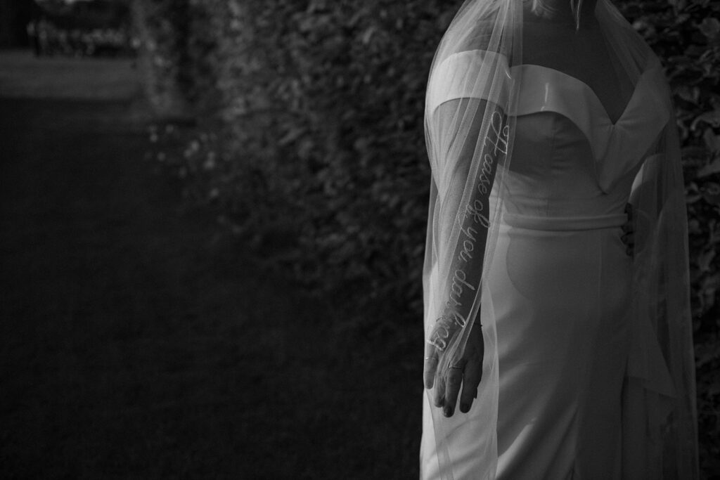 A bride showcasing her veil during sunset at their luxury wedding venue in monochrome