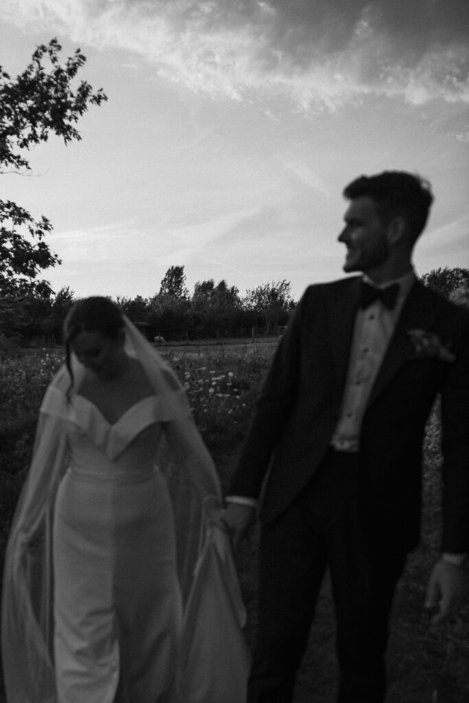 Monochrome blurry image of a wedding couple walking in wildflowers