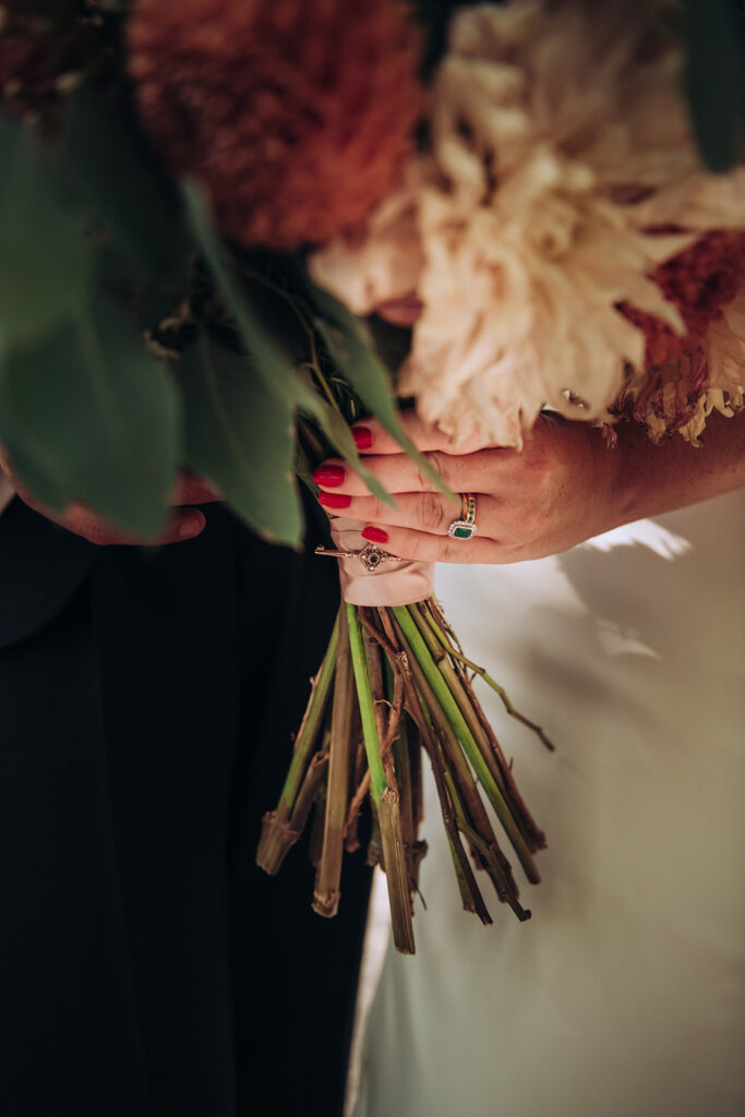 A bride holding her wedding bouquet at the front of her wedding venue, behind the scenes of Editorial Wedding Photography: A Luxury Couple's Shoot in monochrome