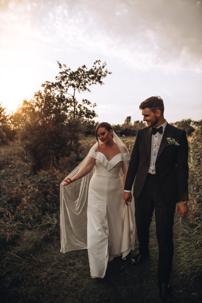 A bride enjoying her veil in wildflowers during sunset at their luxury wedding venue