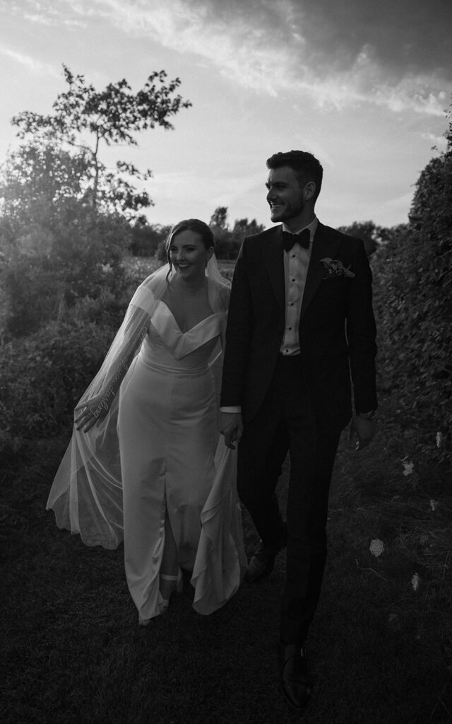 Monochrome image of a wedding couple walking in wildflowers