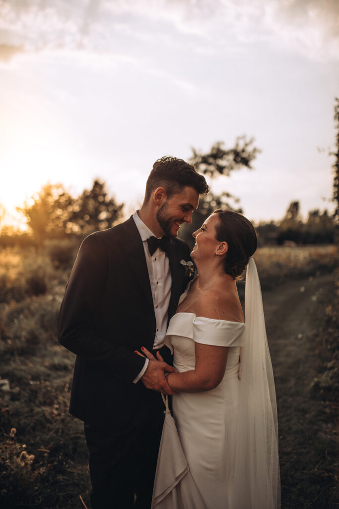 A couple smiling in wildflowers during sunset at their luxury wedding venue