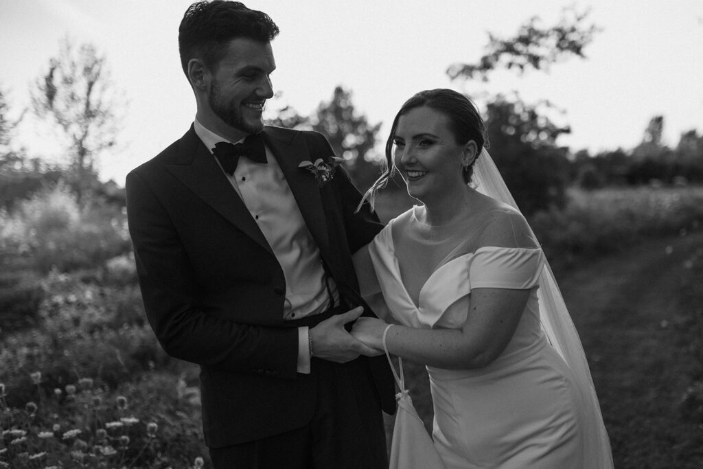 Monochrome image of a wedding couple dancing in wildflowers