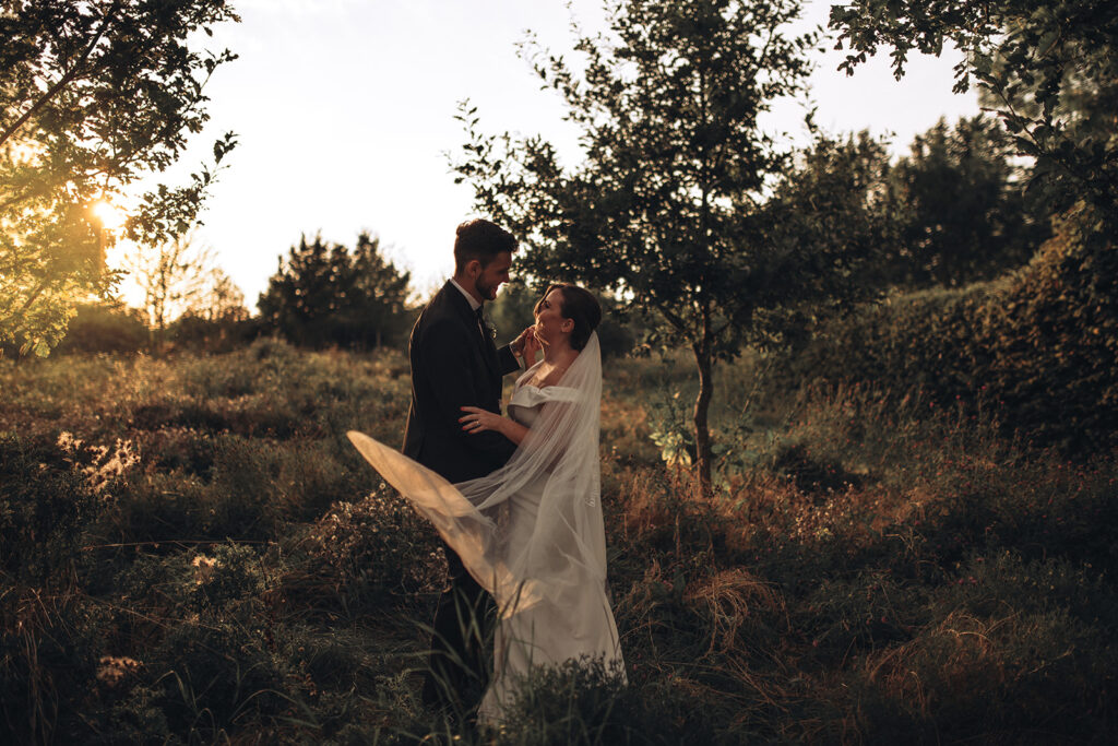 A couple hugging in wildflowers during sunset at their luxury wedding venue