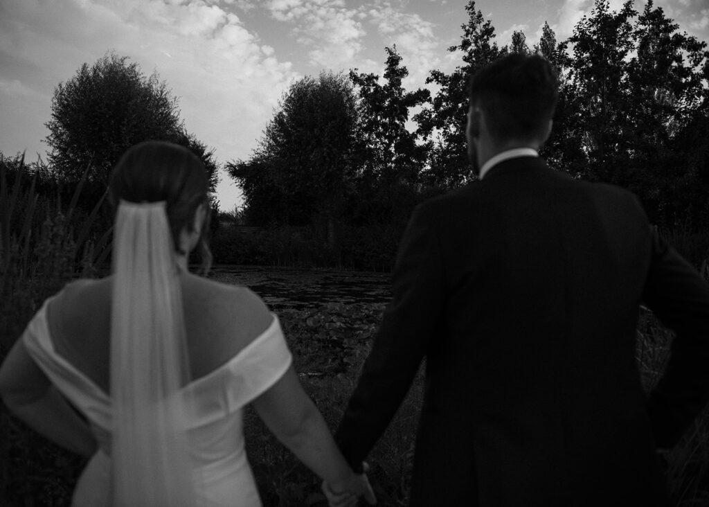 A couple looking over a lake during sunset at their luxury wedding venue in monochrome