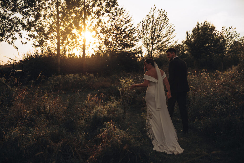 A couple walking in wildflowers during sunset at their luxury wedding venue, behind the scenes of Editorial Wedding Photography: A Luxury Couple's Shoot