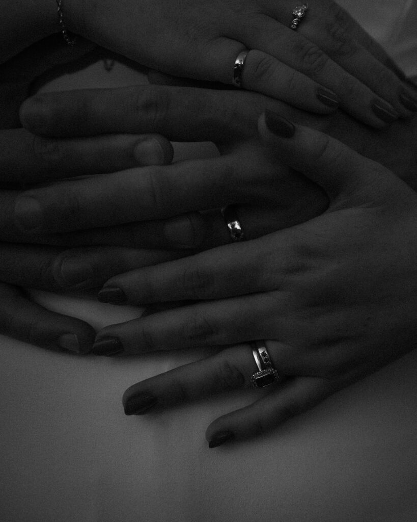 Editorial photograph of a wedding couples wedding rings on hands in monochrome