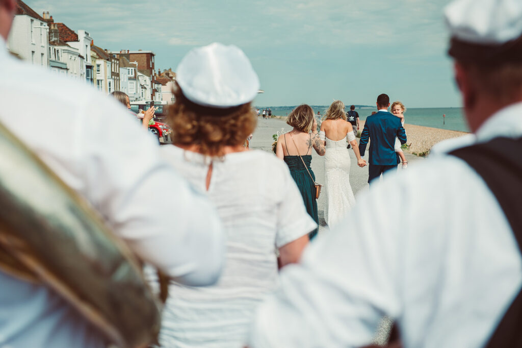 Newlywed couple and their daughter walking across the prom on the beach in Deal Kent