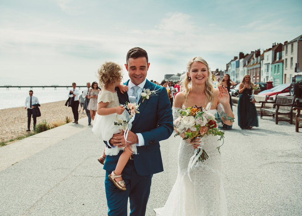 Newlywed couple and their daughter walking across the prom on the beach in Deal Kent