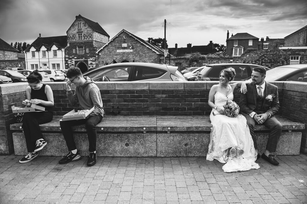 Newlywed couple admiring another couple eating pizza on the quay in Sandwich