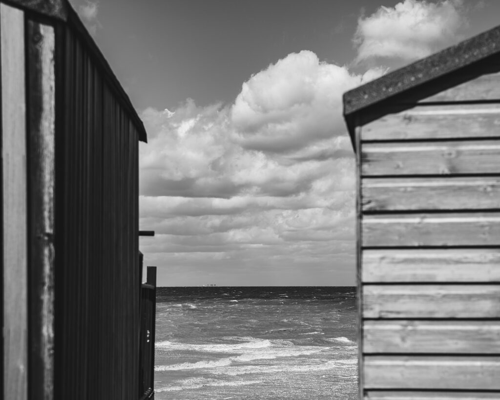 Windy weather in between the beach huts at East Quay in Whitstable