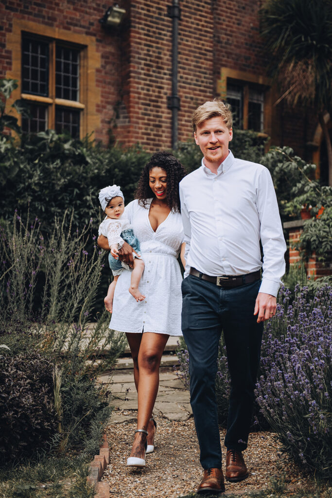 Family walking with their daughter in arms on a photo shoot at Westcott House in Cambridge